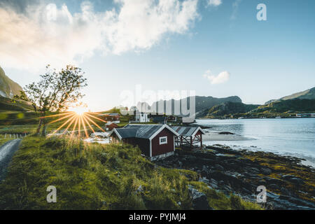 Tradizionale in rosso fishin casa in Bjoernsand vicino a Reine in Lofoten, Norvegia con red rorbu case. Pomeriggio al Tramonto con le nuvole su di una spiaggia di sabbia. Foto t Foto Stock