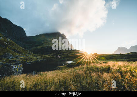 Tradizionale in rosso fishin casa in Bjoernsand vicino a Reine in Lofoten, Norvegia con red rorbu case. Pomeriggio al Tramonto con le nuvole su di una spiaggia di sabbia. Foto t Foto Stock