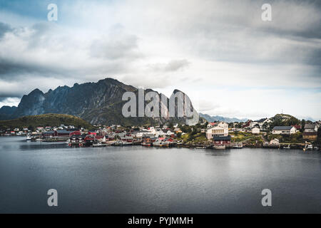 Paesaggio del paesino di pescatori Reine con la Reine Fjord durante il tramonto con belle luci sulla montagna, cielo blu e nuvole. Lofoten, Norvegia. Foto scattata Foto Stock