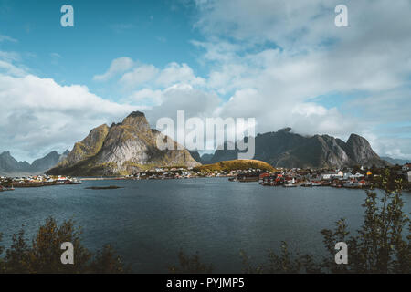 Paesaggio del paesino di pescatori Reine con la Reine Fjord durante il tramonto con belle luci sulla montagna, cielo blu e nuvole. Lofoten, Norvegia. Foto scattata Foto Stock