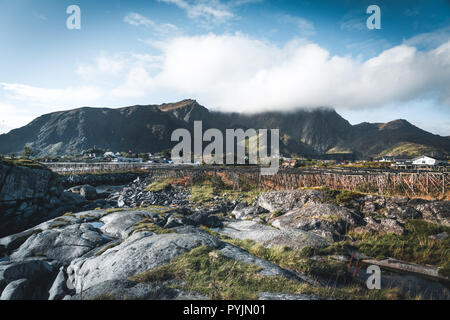 Rainbow ofer case rosso rorbuer di Reine in Lofoten, Norvegia con red rorbu case, nuvole, pioggia cielo azzurro e soleggiato. I ponti e le montagne nella parte posteriore Foto Stock