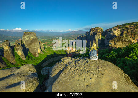 Donna traveler in appoggio a Meteora paesaggio in appoggio a Meteora si affacciano in Tessaglia, Grecia. Escursionista femmina seduto su di una roccia su oper air. Punto di osservazione migliore Psaropetra. Il turismo in Europa. Foto Stock