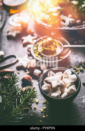 La tazza con il marshmallows e cannella stella di Natale su cookie dark tavolo rustico con i dadi , cioccolato e brunch di fir. Foto Stock