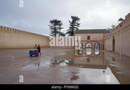 Uomo con ruota barrow in parte anteriore del Bab El Mechouar su Place Moulay Hassan a Essaouira, Marocco, Africa Foto Stock