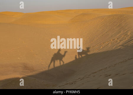 Le ombre dei piloti del cammello nel deserto di Sam, vicino a Jaisalmer, Rajasthan, India Foto Stock