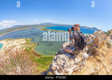 Femmina di viaggio prende colpi di scenic Voidokilia Beach dal castello di Navarino rovina in Pylos, Peloponneso e Grecia dopo escursioni.escursionista donna fotografa un greco popolari punti di riferimento. Fish Eye Foto Stock