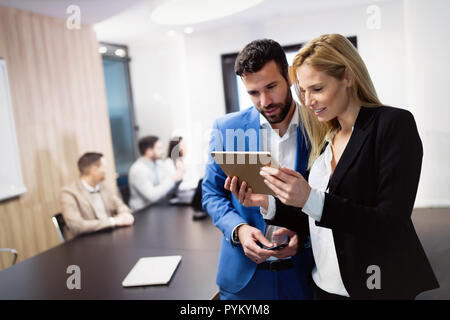 Aziendale attraente giovane utilizzando tablet in loro compagnia Foto Stock