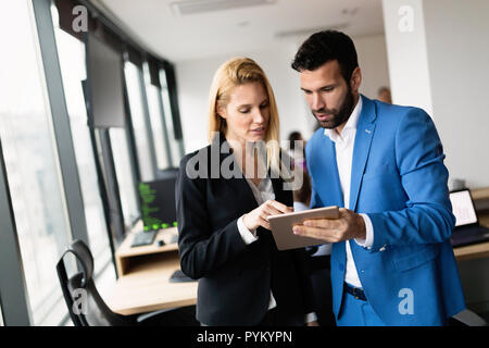 Aziendale attraente giovane utilizzando tablet in loro compagnia Foto Stock