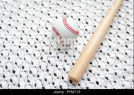 Toy mazza da baseball e la sfera su un fatto a mano maglia bianca coperta con spazio per copiare il testo. Foto Stock