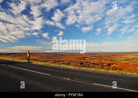 Una donna sguardi sulla brughiera presso il North York Moors nel North Yorkshire, Inghilterra, Regno Unito su una luminosa giornata autunnale Foto Stock