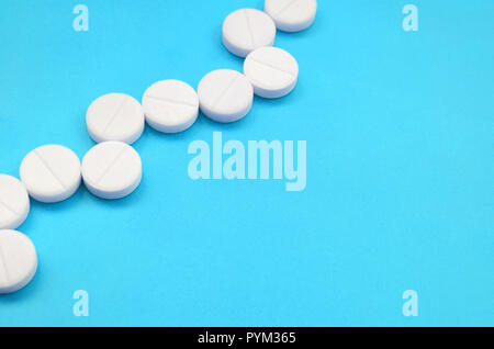 Un paio di compresse bianche giacciono su un blu brillante superficie di sfondo. Immagine di sfondo sul farmaceutico e medico, argomenti Foto Stock