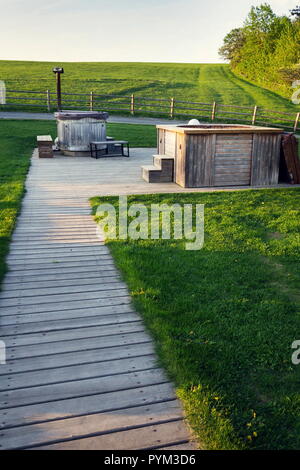 Vasca idromassaggio in legno e vasca calda durante il tramonto in bella estate paesaggio rurale Foto Stock