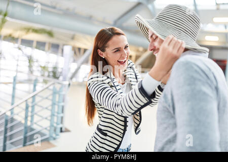 Ridendo giovane donna mettendo un estate hat sul suo partner prima di partire per le vacanze Foto Stock