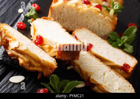 In casa a fette di latte condensato il pane con le ciliegie secche, le mandorle e le foglie di menta vicino sul tavolo orizzontale. Foto Stock