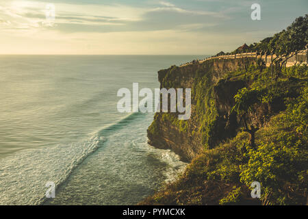 Cliff, ocean shore, percorso turistico. Panorama. Uluwatu. Isola di Bali. Indonesia. Uno splendido scenario di alta verde-capped rock sull'Oceano Indiano. Shot t Foto Stock