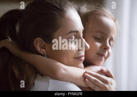 Offerta attraente madre cuddling piccola figlia in età prescolare Foto Stock