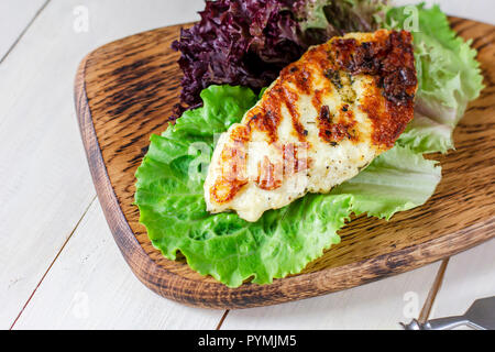 Grigliata in casa il formaggio halloumi con spezie su tavola di legno con fresche foglie di lattuga Foto Stock