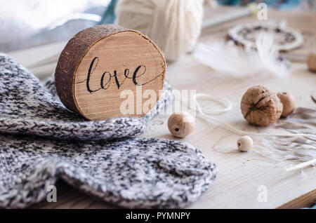 Composizione con l'iscrizione di amore, di legno e di elementi a maglia. Accogliente fotografia nello stile di un hugge. Foto Stock