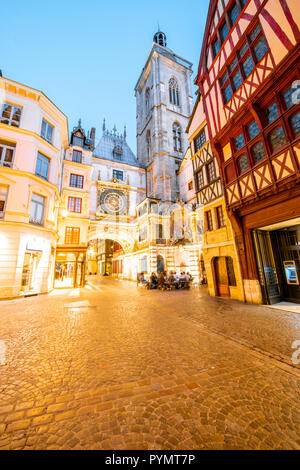 Street view con edifici illuminati e la famosa torre dell'orologio durante il crepuscolo nel centro storico della città di Rouen in Francia Foto Stock