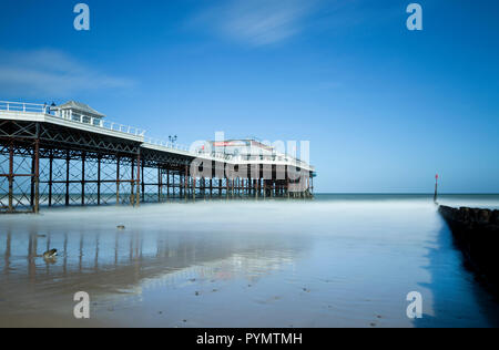 Cromer Pier con onde si fonde con la nebbia a Cromer Beach in Norfolk England Regno Unito Foto Stock