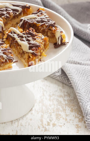 Frische Nussecken auf einer weißen Porzellan Kuchenplatte dekoriert mit Backzutaten Foto Stock