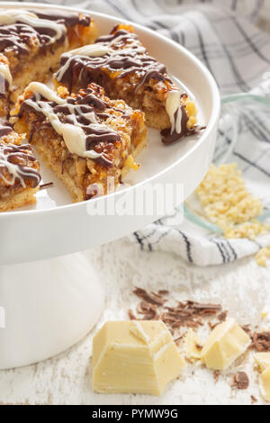 Frische Nussecken auf einer weißen Porzellan Kuchenplatte dekoriert mit Backzutaten Foto Stock