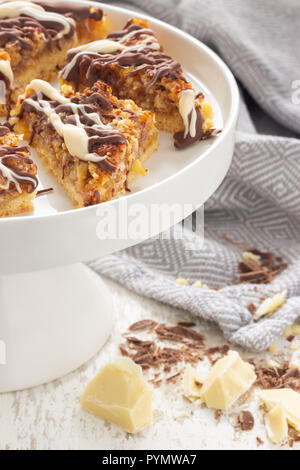 Frische Nussecken auf einer weißen Porzellan Kuchenplatte dekoriert mit Backzutaten Foto Stock