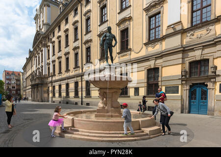 Wroclaw street, vista dell'Università di Wroclaw edificio nel Plac Uniwersytecki con una famiglia polacca giocando alla base del Fencer Fontana. Foto Stock