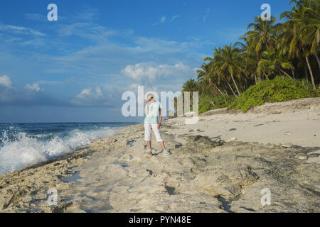 Giovane bella donna in giallo occhiali da sole su di una spiaggia di Coral Foto Stock