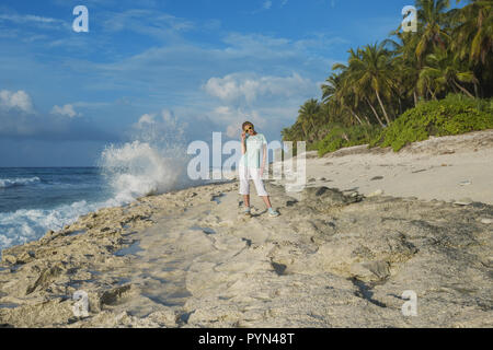 Giovane bella donna in giallo occhiali da sole su di una spiaggia di Coral Foto Stock