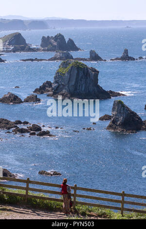 Gueirua beach, Asturias, Spagna. Vista verticale dal lato opposto della montagna di una baia piena di barriere coralline che si stagliano dell'acqua e di una donna. Foto Stock