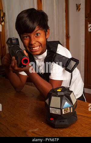 Ragazzo latino a giocare con un gioco di laser rifle Foto Stock