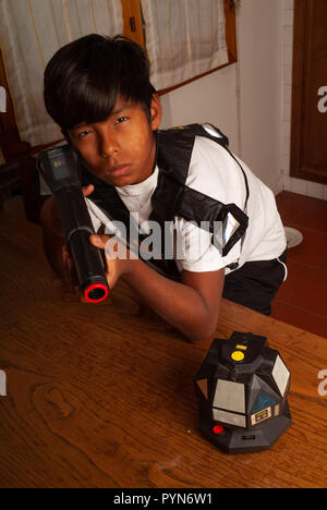 Ragazzo latino a giocare con un gioco di laser rifle Foto Stock