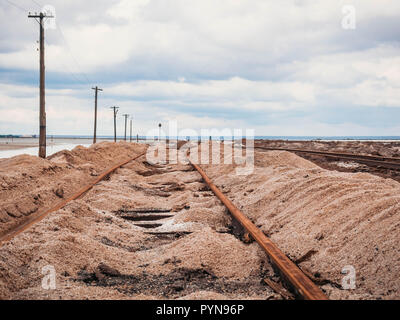 Rusty razy rotaie e traversine marcio coperto di sale sulla vecchia ferrovia tracce su una collinetta a miniere di sale vicino lago di salamoia. Foto Stock