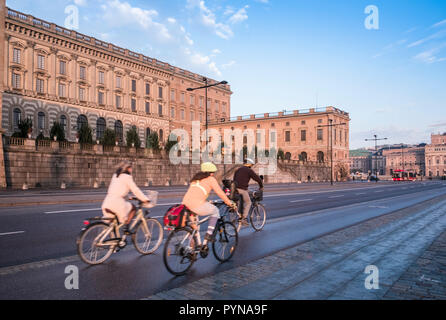 Tre eco friendly ciclisti utilizzare una bicicletta corsia sulla strada Skeppsbron al di fuori del Palazzo Reale, la Gamla Stan, Stoccolma, Svezia Foto Stock