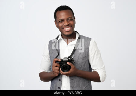 Ritratto di fiducia del giovane africano in camicia e gilet tenendo la fotocamera foto Foto Stock