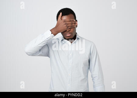 Oung african Uomo in camicia bianca che copre gli occhi Foto Stock
