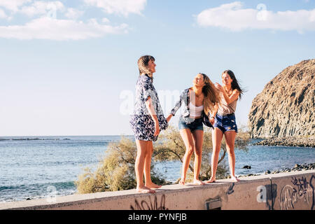 Tre attraenti ragazze giocare e divertirsi insieme all'esterno le attività per il tempo libero con oceano in background. orario estivo e di amicizia per Nizza cheerf Foto Stock