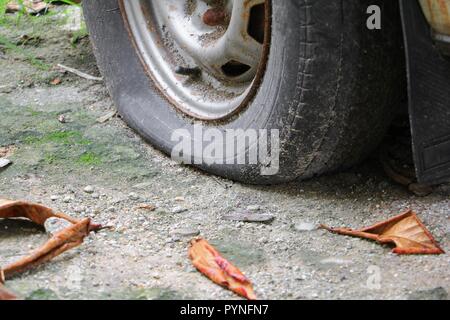 Chiudere la ruota ruota sgonfia e della vettura vecchia e incrinato su strada Foto Stock