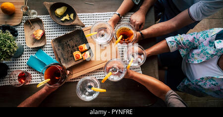 Al di sopra di vista della popolazione caucasica in amicizia tutti insieme a bere e festeggiare con vino rosso e bianco per cocktail party yime. Tavolo in legno e fo Foto Stock