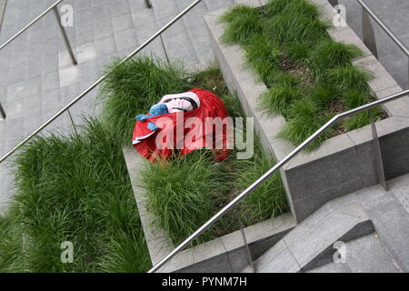 Una ragazza in abito rosso i performa performance artistica in uno spazio pubblico. Molto elegante e brave le prestazioni nel centro della città di Milano. Foto Stock
