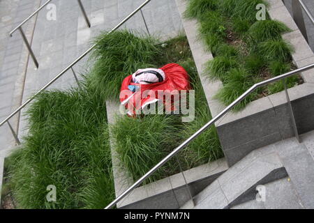 Una ragazza in abito rosso i performa performance artistica in uno spazio pubblico. Molto elegante e brave le prestazioni nel centro della città di Milano. Foto Stock