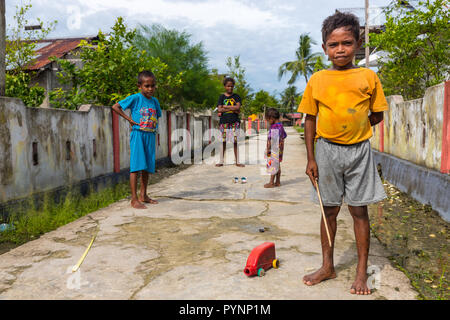 Villaggio TUNGU, isole Aru, Indonesia, dicembre 06, 2017 : i ragazzi giocare con la plastica può auto nella strada del villaggio di Tungu, isole Aru, Papua, Indo Foto Stock