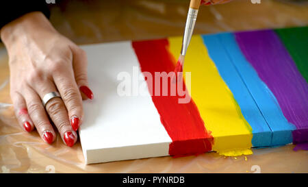 Artista femminile dipinto un arcobaleno con colori acrilici su tela, hoe arte, DIY tutorial, colorato Foto Stock