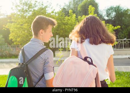 I bambini gli adolescenti vanno a scuola, vista posteriore. All'aperto, ragazzi con zaini. Foto Stock