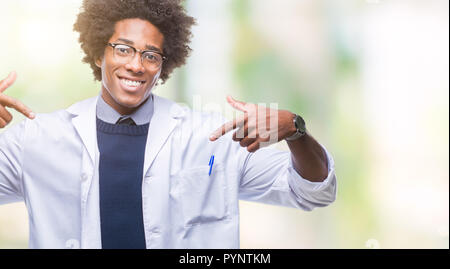 Afro American medico scienziato uomo sullo sfondo isolato guardando fiduciosi con il sorriso sul volto, rivolto a se stessi con le dita orgogliosa e felice. Foto Stock