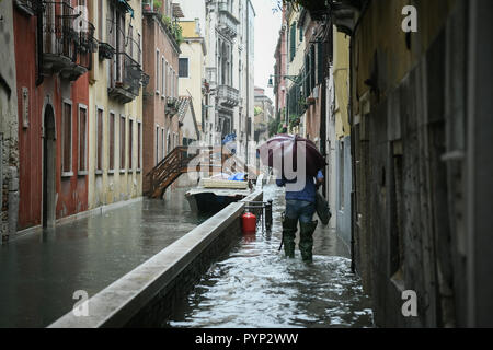 Venezia, Italia. 29 ottobre, 2018. Un uomo con ombrellone e wellies passeggiate con wellies durante l eccezionale Acqua Alta - Alta Marea inondazioni in Venezia, Italia il 29 ottobre 2018. Il 70% della città lagunare è stata inondata dalle acque rising 149 centimetri sopra il livello del mare. Credito: Piero Cruciatti/Alamy Live News Foto Stock