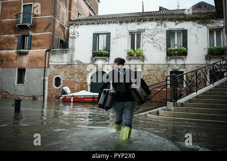 Venezia, Italia. 29 ottobre, 2018. Un turista portare bagagli durante l eccezionale Acqua Alta - Alta Marea inondazioni in Venezia, Italia il 29 ottobre 2018. Il 70% della città lagunare è stata inondata dalle acque rising 149 centimetri sopra il livello del mare. Credito: Piero Cruciatti/Alamy Live News Foto Stock