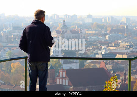 Tourist fuori fuoco guardando il panorama di Vilnius, Lituania con il gotico chiesa di Sant'Anna Foto Stock