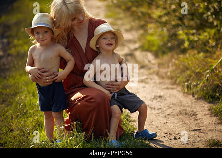 Bella madre abbraccia i suoi diletti figli gemelli Foto Stock